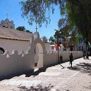 Fachada de la Iglesia de San Pedro en la plaza principal de San Pedro de Atacama, rodeada de adobe tradicional y cielo azul